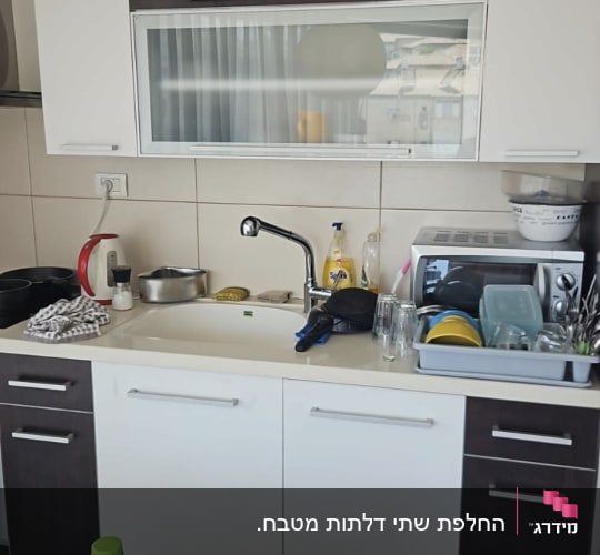 מטבח עם כיור, כלים ומכשירי חשמל על השיש